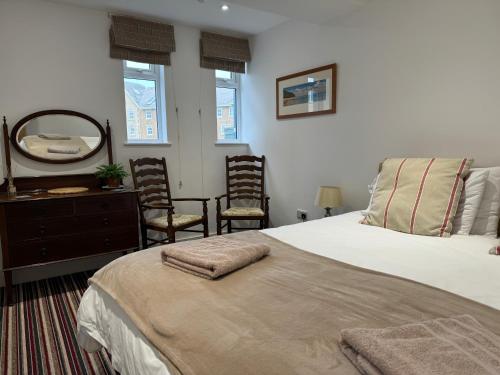a bedroom with a bed and chairs and a mirror at The Pilot Boat Inn, Isle of Wight in Bembridge