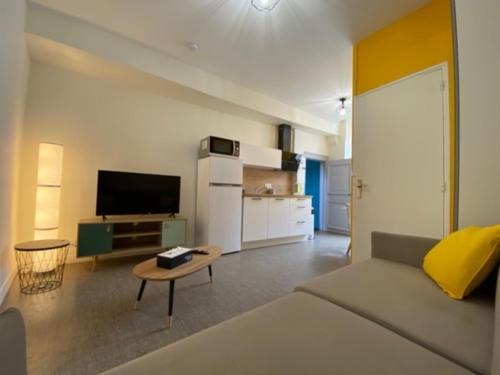 un salon avec un canapé et une télévision et une cuisine dans l'établissement Ecole 101, à La Flèche