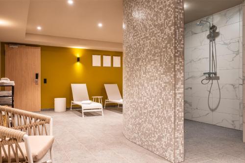 La salle de bains est pourvue d'une douche et de chaises. dans l'établissement Leonardo Hotel Hamburg Altona, à Hambourg