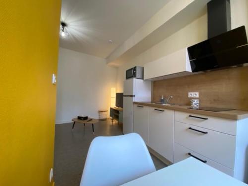 une cuisine avec des placards blancs et un mur jaune dans l'établissement Ecole 101, à La Flèche