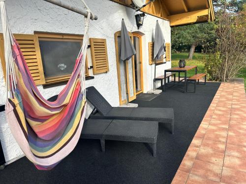 a hammock hanging from a house with a tv at Ferienhaus Veronika mit 2000qm Garten und Bergblick in Unterammergau