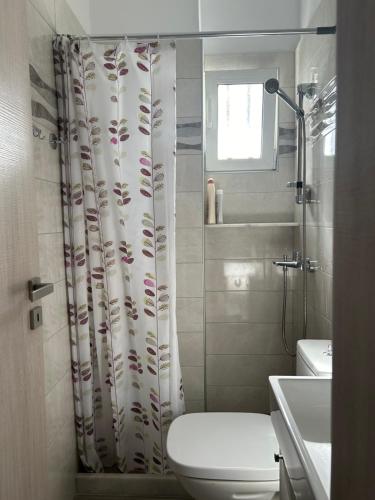 a bathroom with a toilet and a shower curtain at Evelyn's Cozy Apartment in Rhodes Town