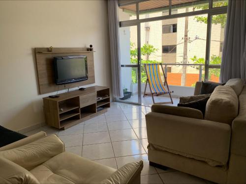 uma sala de estar com 2 sofás e uma televisão de ecrã plano em Apartamento no Guarujá para 8 pessoas no Guarujá