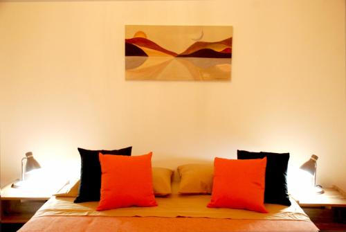 1 cama con almohadas de color naranja y una pintura en la pared en Departamento en Flores, Ciudad de Buenos Aires en Buenos Aires