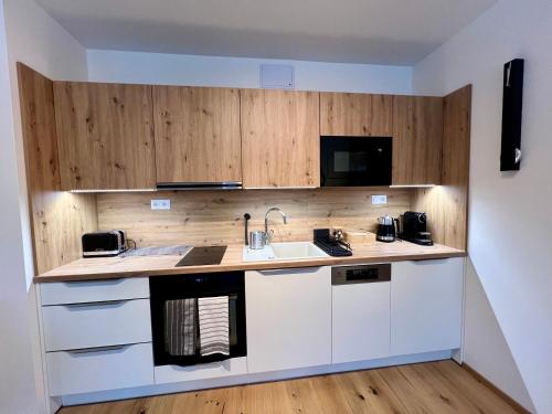 a kitchen with white cabinets and a sink at Golden Ridge Apartments in Špindlerův Mlýn