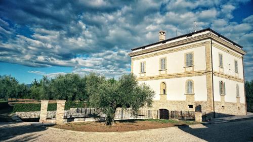 a large white building with a tree in front of it at Il Casino di Remartello in Loreto Aprutino