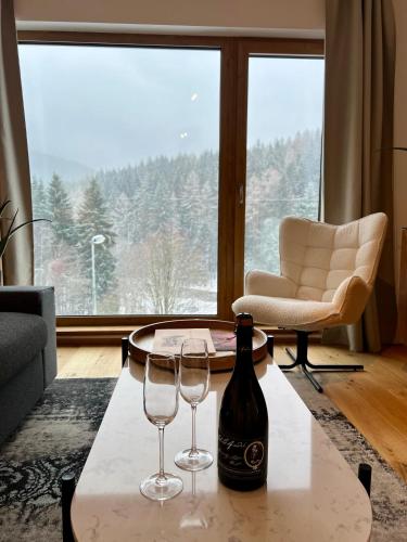 a living room with a bottle of wine and two glasses on a table at Golden Ridge Apartments in Špindlerův Mlýn