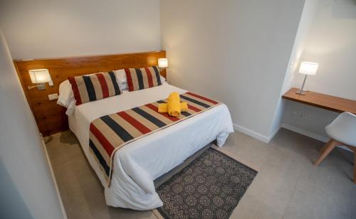 Un dormitorio con una cama con un osito de peluche amarillo. en Playas Art Hotel en Pinamar