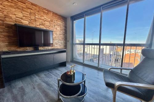 - un salon avec une télévision, un canapé et une chaise dans l'établissement LES PIEDS DANS L'EAU - Magnifique P2 proche de la mer, au Grau-du-Roi