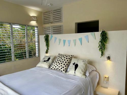 a bedroom with a bed with white sheets and a tv at Villa Vertigo-Vista Linda in Río San Juan