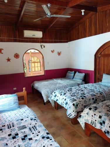 a room with three beds and a mirror at Las cabinas del sueño in Nicoya