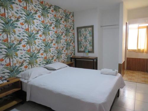 1 dormitorio con cama blanca y papel pintado con motivos florales en Hotel Costa Inn, en Panamá