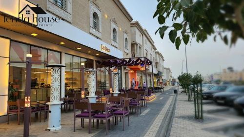 a row of tables and chairs on a city street at Lenda House in Al Madinah