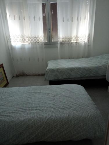 twee bedden in een kamer met witte gordijnen bij T4 Prado vélodrome plage 3 chambres in Marseille