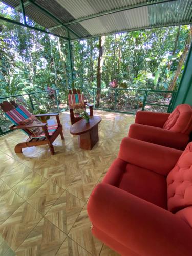 sala de estar con sofá rojo y sillas en Grettel´s House Apartments, La Fortuna de San Carlos, en Fortuna