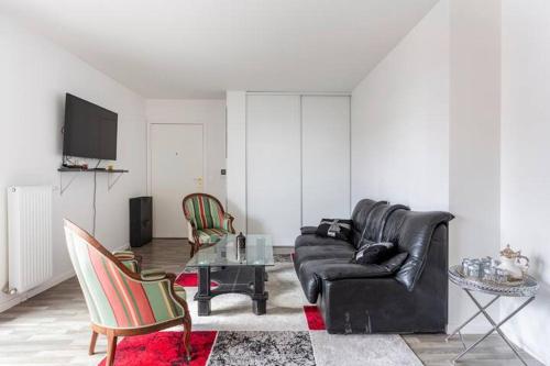 a living room with a black leather couch and chairs at Chambre Double a proximité de Paris in Saint-Denis