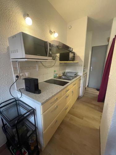 une cuisine avec un évier et un micro-ondes dans l'établissement Tennis Village avec terrasse, piscine, clim et parking, au Cap d'Agde