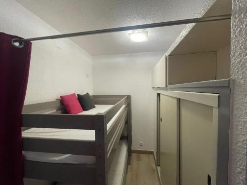 Cette petite chambre comprend un lit superposé avec un oreiller rouge. dans l'établissement Tennis Village avec terrasse, piscine, clim et parking, au Cap d'Agde