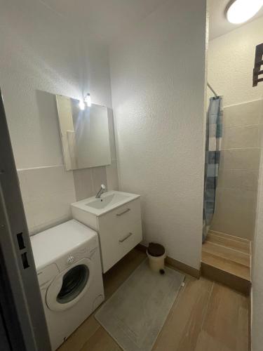une salle de bain avec une machine à laver et un lavabo dans l'établissement Tennis Village avec terrasse, piscine, clim et parking, au Cap d'Agde