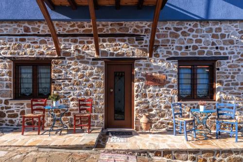 une maison en pierre avec des chaises bleues et rouges et une porte dans l'établissement Άρνη' κόρη του Αιόλου 2, à Arnaia
