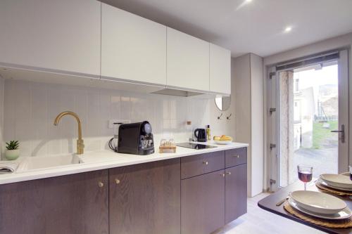 a kitchen with white cabinets and a sink at La Suite Rosièroise in Rosières