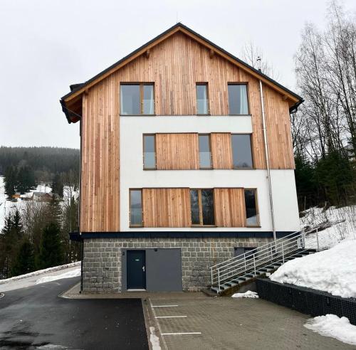 a house with a wooden facade in the snow at Golden Ridge Apartments in Špindlerův Mlýn
