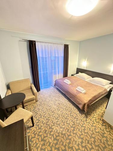 a hotel room with a bed and a chair at Baltic Sun SPA in Rewal