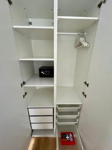 a white closet with white shelves and a red box at Golden Ridge Apartments in Špindlerův Mlýn