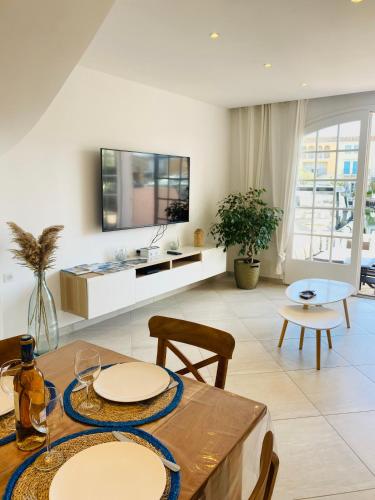 a living room with a table and chairs and a tv at Maison de pêcheur Strelitzia amarrage 3,8m par 16m in Grimaud