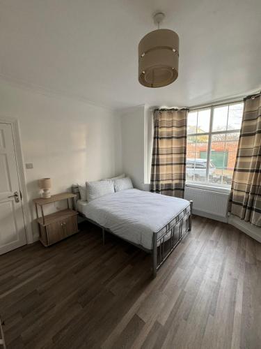ein Schlafzimmer mit einem Bett und einem großen Fenster in der Unterkunft Oxborne Rooms UK - Gardner in London