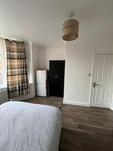 Schlafzimmer mit einem weißen Bett und einem Kühlschrank in der Unterkunft Oxborne Rooms UK - Gardner in London