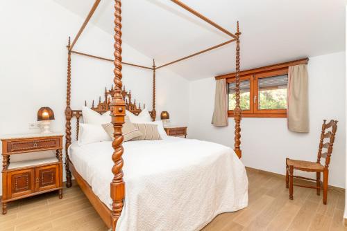 ein Schlafzimmer mit einem Himmelbett und einem Stuhl in der Unterkunft El Huerto - Großzügiges Appartment in Katalanischer Masia in Sant Iscle de Vallalta