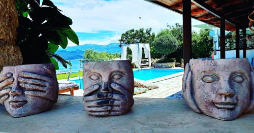 four face head pots sitting next to a pool at Luxury Villa Athina in Nikiana