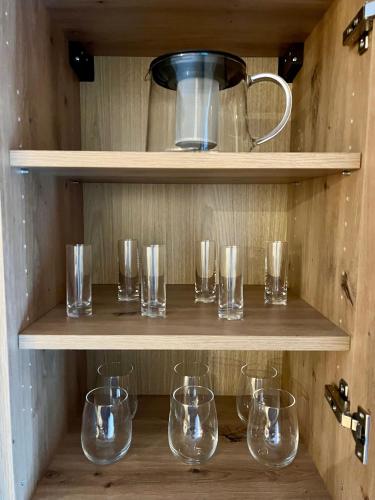 a row of glasses sitting on wooden shelves at Golden Ridge Apartments in Špindlerův Mlýn