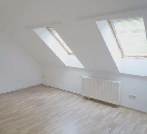 an empty white room with two windows and a wooden floor at Helle Wohnung mit modernen Flair in Steinfeld