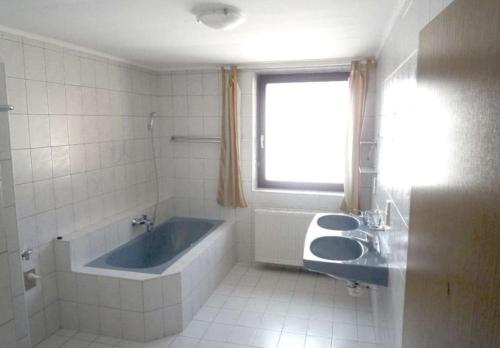 a bathroom with a tub and two sinks and a window at Helle Wohnung mit modernen Flair in Steinfeld