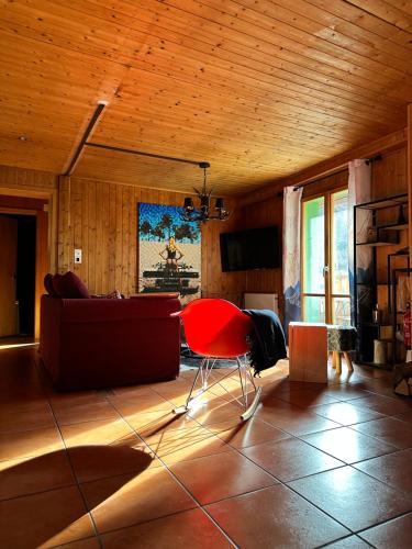 a living room with a couch and a red chair at Bel appartement près de Verbier in Bovernier
