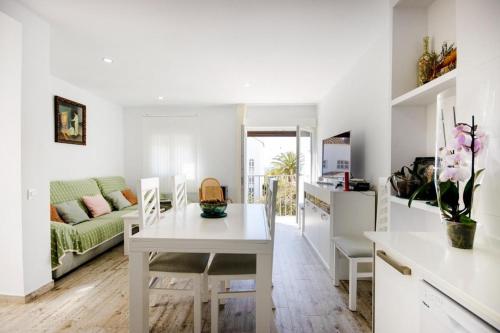 a white kitchen and living room with a table and chairs at Zahara Pueblo villas y apartamentos in Zahara de los Atunes