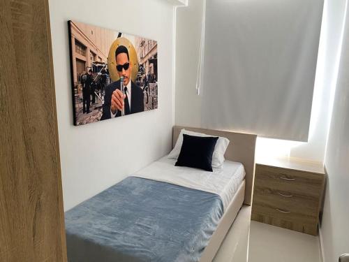 1 dormitorio con 1 cama y una foto en la pared en Nuevo a 10 minutos de Buenavista, en Puerto Colombia
