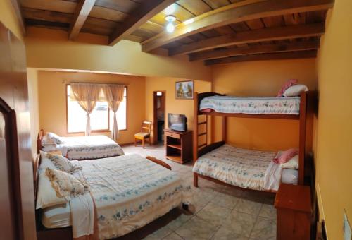 een slaapkamer met 2 stapelbedden en een televisie bij HOTEL LAS TANGARAS DE MINDO in Mindo
