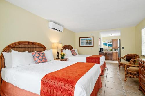 a hotel room with two beds and a chair at Coconut Bay Resort - Key Largo in Key Largo