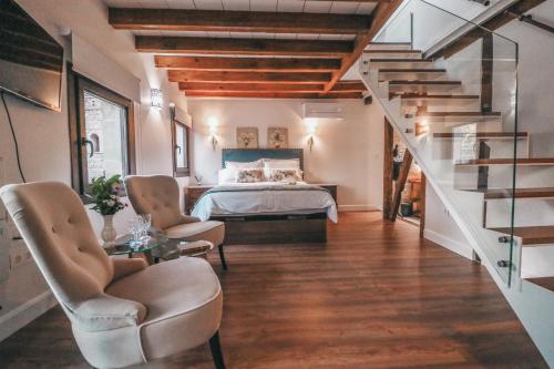 a bedroom with a bed and two chairs and a staircase at Casa Airosas in Toledo