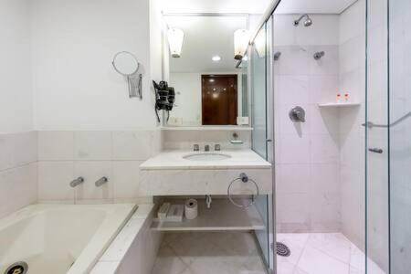 a white bathroom with a sink and a shower at B Homy Itaim - Condomínio completo GEO206 in São Paulo