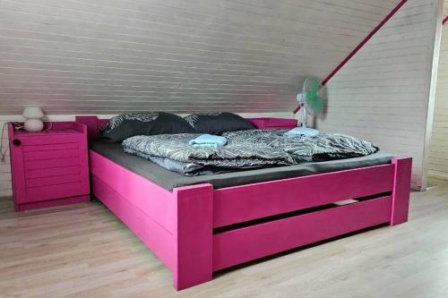 a pink bed in a room with a wooden floor at Orhideja in Brežice