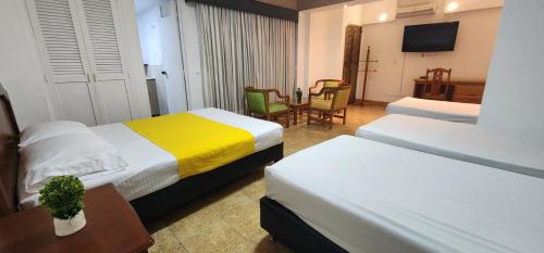 a hotel room with two beds and a table at Hotel Laureles 70 in Medellín