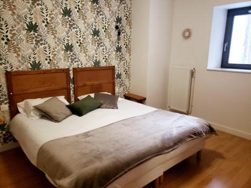 una camera da letto con un letto con lenzuola bianche e cuscini verdi di Restaurant Hôtel du Vercors a Saint-Martin-en-Vercors