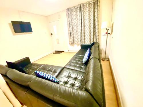 um sofá de couro numa sala de estar com almofadas em Spacious Ground Floor Two Bedroom house on in Ealing London em Ealing