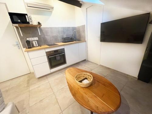 une petite cuisine avec une table en bois et une télévision dans l'établissement Petit Studio Cannes - 5min Plages & Gare & Palais des Festivals - Climatisation, à Cannes