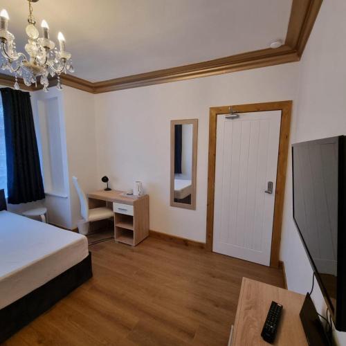 a bedroom with a bed and a desk and a television at Uplands Grove Bungalow in Wolverhampton