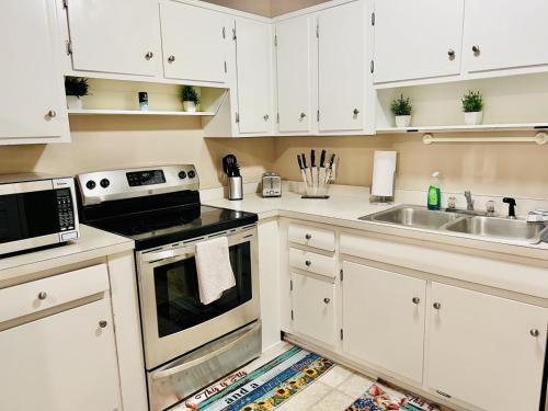 - une cuisine avec des placards blancs et un évier dans l'établissement Cozy 4 bedroom Cottage by Duke Raleigh Hospital, à Raleigh